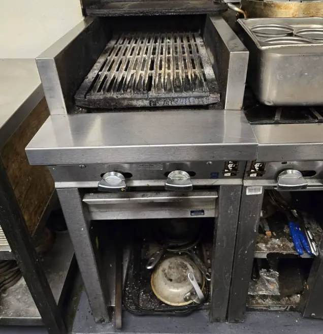 Commercial kitchen charbroiler and fryer station opened up for repair