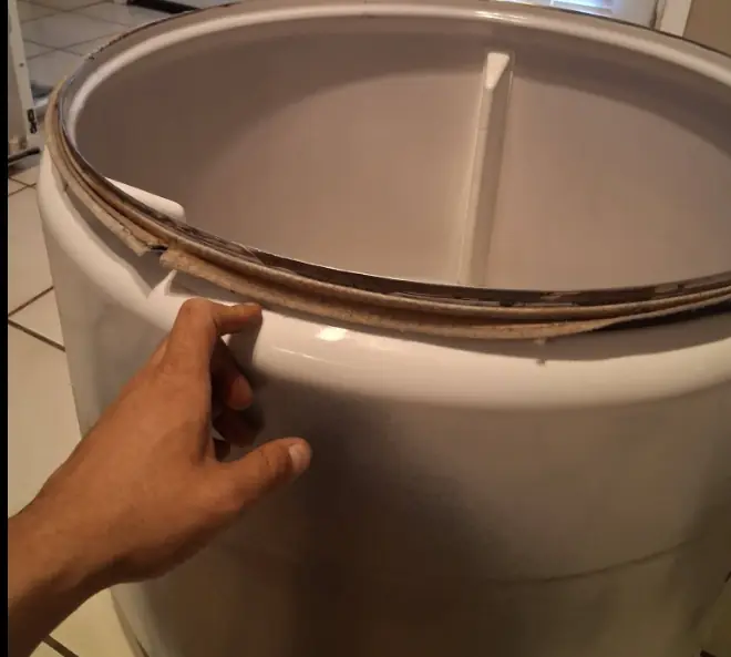 Hand checking the worn felt seal on the edge of a dryer drum