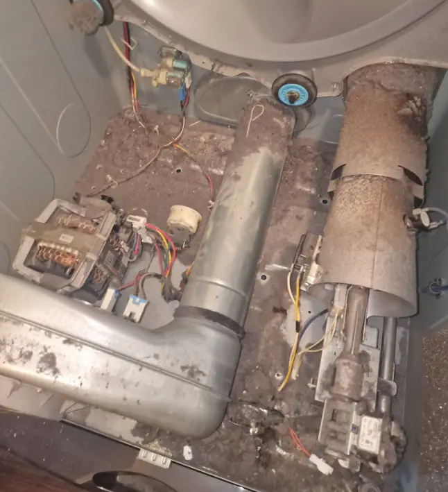 Lint packed inside a dryer cabinet around the heater duct before cleaning