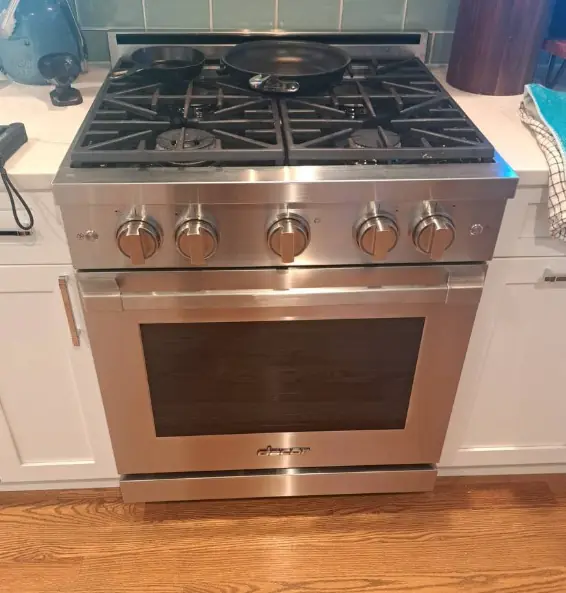 Stainless steel gas range with a five-burner cooktop after repair