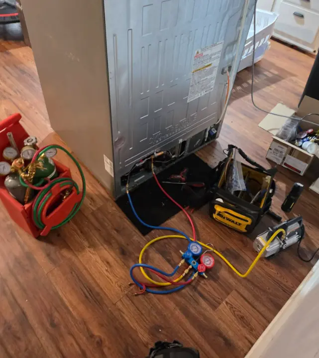 Refrigerant gauges and recovery tools hooked up to a refrigerator for sealed system repair