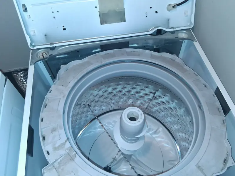 Top-load washer with the lid open showing the wash tub for suspension repair
